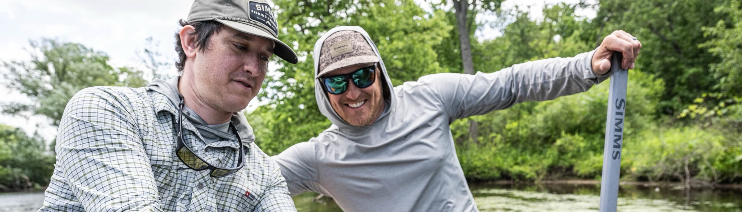 Two anglers fishing a summer river from a jon boat