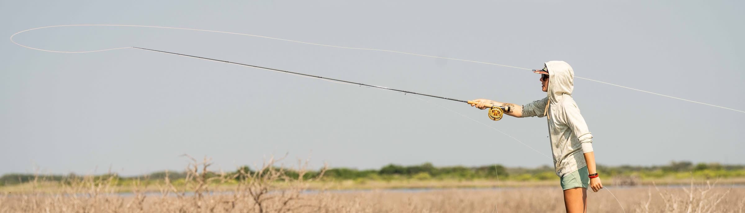 A fly line loop unrolling over a coastal marsh