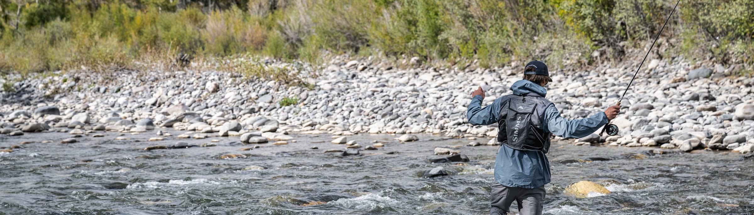 An angler wading a wide cobble-bottomed river