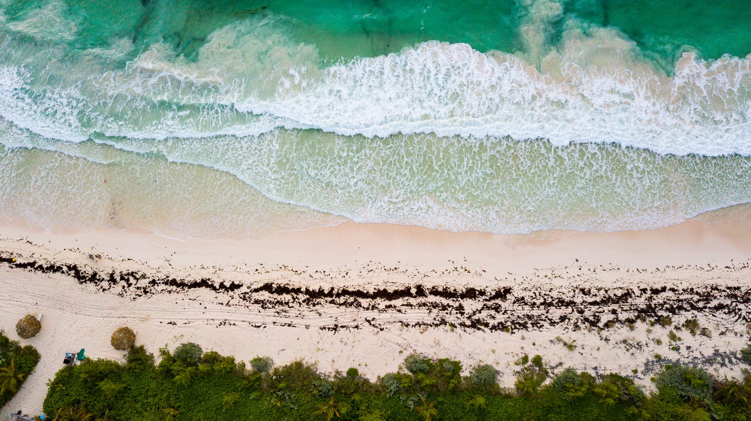 Surf breaking along a beach, from above