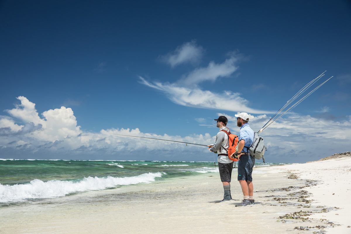 Two anglers on a Seychelles surf beach, rod held out across breaking water